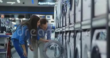 年轻的已婚夫妇男女在休闲服装电器商店选择买洗衣机回家。 打开门
